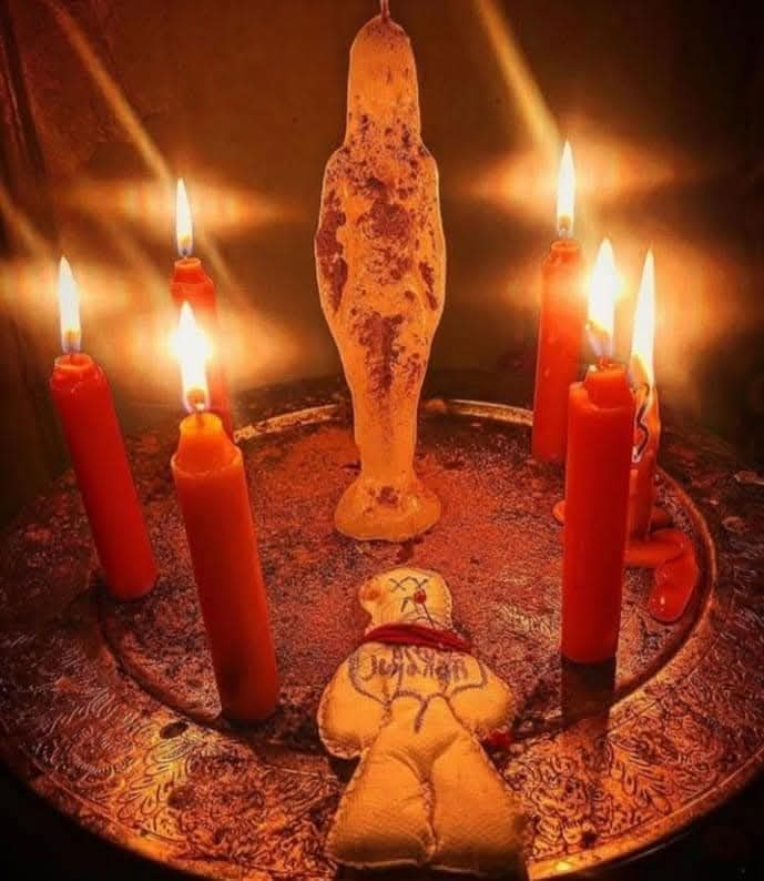 Velas rojas encendidas alrededor de figuras rituales